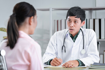 Fototapeta premium Asian male doctor talking to a patient to maintain the health of the patient Providing health advice to patients at the hospital