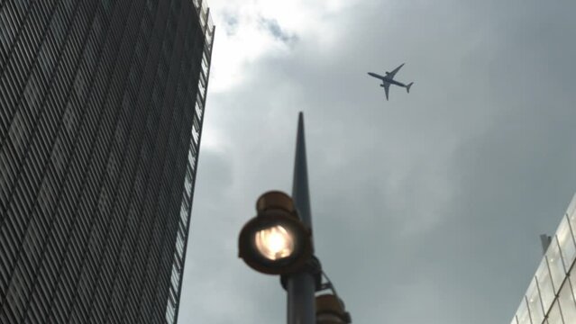 Airplane Flight Over Business Center Of Skyscrapers At London. Bottom View Of High-rise Buildings With Flying Plane In Blue Sky With Clouds in Afternoon. Air Transport, Travel, Vocation concept.