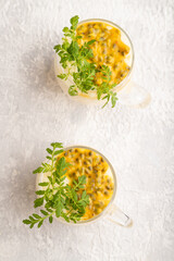 Yogurt with passionfruit and marigold microgreen in glass on gray. Top view.