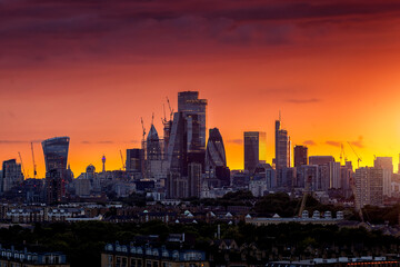 Obraz premium The modern skyline of the City of London during a fiery summer sunset with the skyscrapers reflecting the warm sunlight