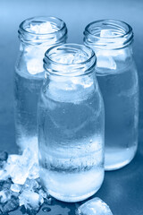 Glass bottles with cold water and ice