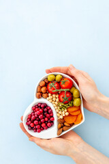Hands holding heart shaped dish full of healthy diet food - obrazy, fototapety, plakaty