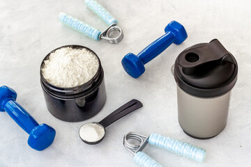 Sport bottle and jar of powder whey protein and dumbbells. Fitness and gym diet