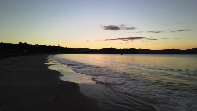 Floating Across The Small Waves Of Cooks Beach At Sunset