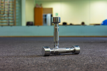 Two shiny chrome plated fitness dumbbells in the gym hall