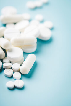 Various white pills on blue background.
