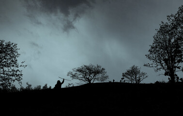 Man holding a stick among dark trees