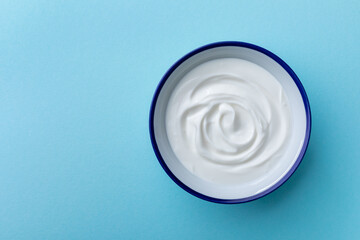 Greek yogurt in bowl on blue table top view.