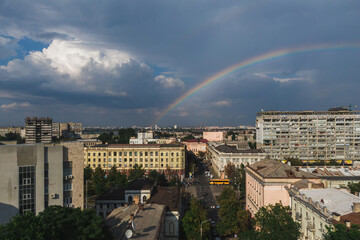 Beautiful rainbow after the rain on the blue sky and clouds over the city. An amazing natural phenomenon when sunlight is combined with rain. Photo taken from a drone