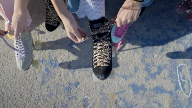 Overhead view of young women&rsquo;s hands tying laces on retro rollerskates