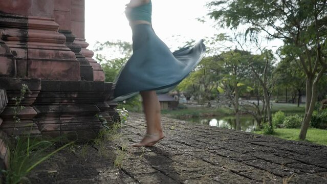 A Woman In Blue Clothing Gracefully Twirling In The Cobblestone Pathway Within The  Ancient Siam Museum, Thai Ban Mai, Thailand. Slow-motion