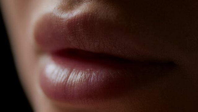 Macro shot of lips of white-skinned female model opening on black background | Lip care concept
