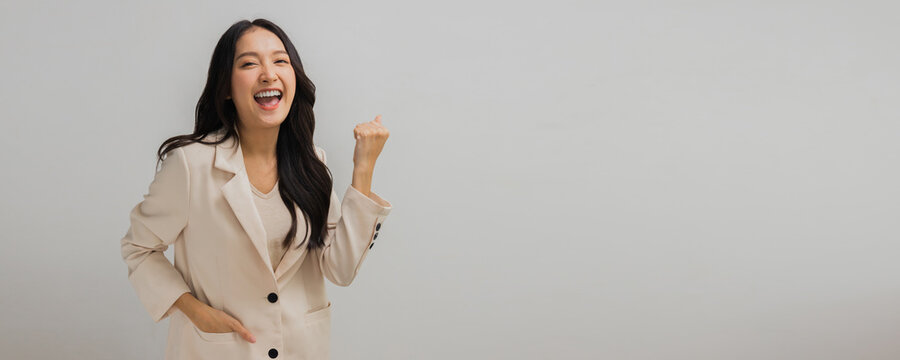 Successful and attractive Asian businesswoman show hand up to celebrate, success and glad woman in white suit isolated in studio