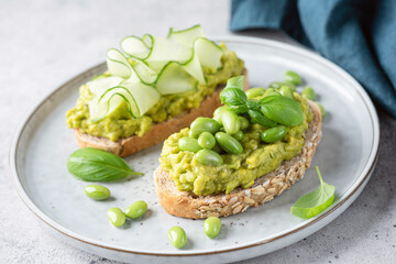 Avocado toasts with edamame beans, cucumber slices and basil. Healthy green vegan food