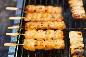 Close up of barbecue grill salmon skewers on wooden sticks, thai street food market