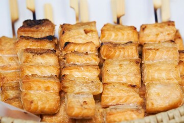 Close up of barbecue grill salmon skewers on wooden sticks, thai street food market