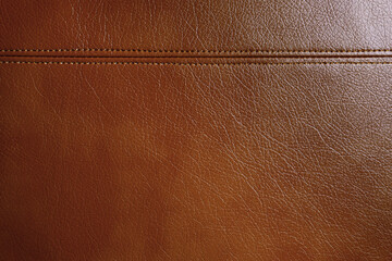 Fototapeta premium Natural, artificial brown leather texture background with decorative seam. Material for sport items, clothes, furnitre and interior design. ecological friendly leatherette.