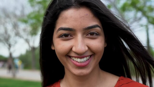 Beautiful young indian woman smiling on camera outdoor	
