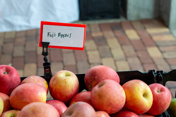 A stack or bulk supply of large organic ripe red Fuji apples on a table for sale at a farmer's...