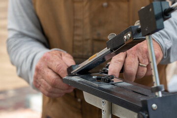 A man using a fixed angle knife sharpener kitchen tools at a farmer's market to sharpen knives for...