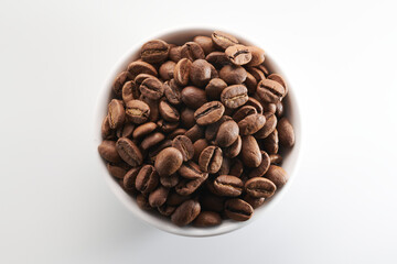 Roasted coffee beans in bowl isolated close up on white background, clipping path