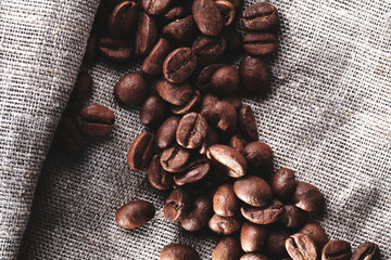 Roasted coffee beans decorated with burlap fabric close up creative background