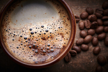 Composition served freshly brewed cup of coffee and roasted coffee beans on brown background, top view