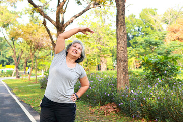 Asian elderly woman exercise in the park in the morning she smiles happy Healthy body. concept of health care for seniors to be healthy
