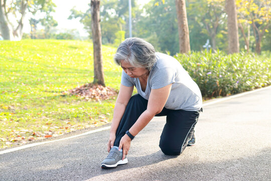 Asian elderly woman jogging in the park in the morning She had an ankle injury from exercising. She felt a lot of pain. concept of health care for seniors to be healthy