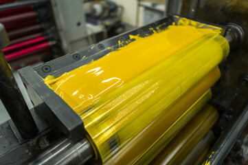Yellow ink in the paint system compartment of a modern flexographic printing press in a print shop....