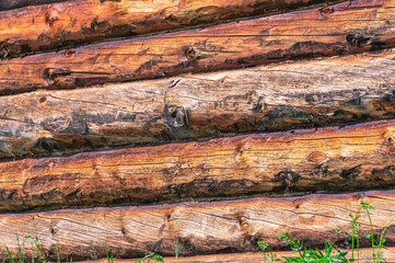 Background of dark wooden cracked logs. The wall of a wooden house. Wooden log house. Aged wood with a brown tinge.