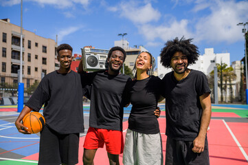 Cheerful black sportspeople with boombox on playground