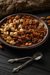 Hazelnuts, cashews, raisins, almonds, peanuts, walnuts on a wooden black background