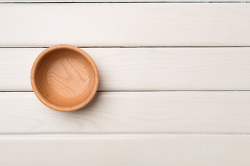 Wooden bowl on wooden background, top view