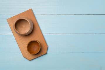 Wooden bowls and board on wooden background, top view