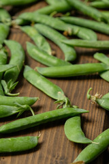 fresh peas on a wooden background, wooden brown table, green homemade peas, creative photo of peas, space for text, tasty and natural peas, photo without processing