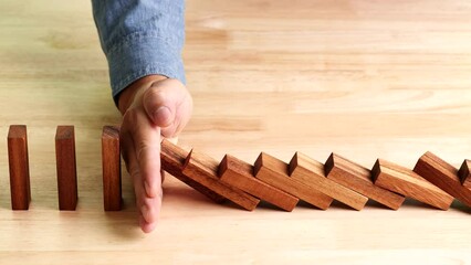 Business crisis, risk management concept, businessman hand stopping or preventing falling dominos effect of risk, business crisis on wooden table, slow motion - Powered by Adobe