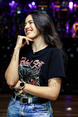 Fancy happy woman posing on a stage of an empty theater lightened by disco globe 
