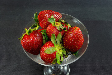strawberries in a tall bowl on a black background close-up