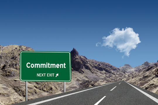 Highway sign with the word Commitment and a metaphoric road leading to future success.