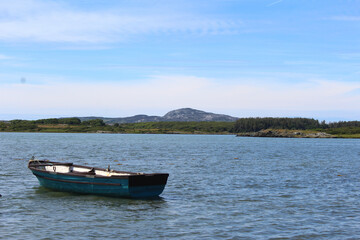 Naklejka na ściany i meble small boat on the calm irish sea in snowdonia, wales with welsh hill landscape in the background 