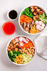 Vegan buddha bowl with tofu, colorful vegetables on base of brown rice.