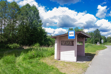 Bus stop on the side of a road in countryside. Station is empty on sunny summer day with beautiful...