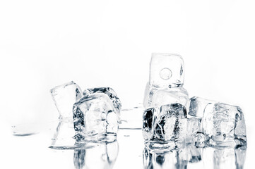 Natural crystal clear melting ice cubes isolated on white. Mirroring reflective surface background.