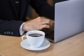 businessman in black suit working at desk with laptop in office