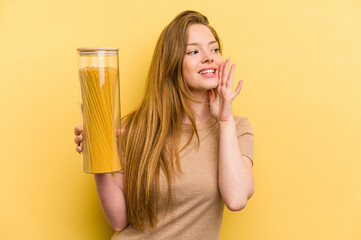 Young caucasian woman holding a spaghettis jar isolated on yellow background shouting and holding palm near opened mouth.