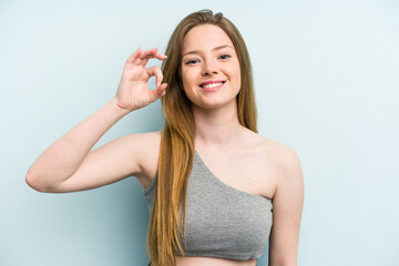Young caucasian woman isolated on blue background cheerful and confident showing ok gesture.