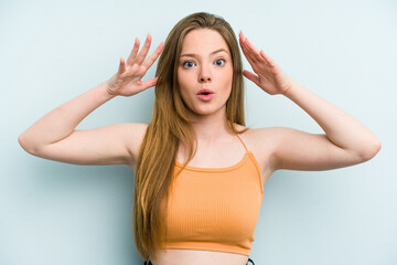 Fototapeta premium Young caucasian woman isolated on blue background celebrating a victory or success, he is surprised and shocked.