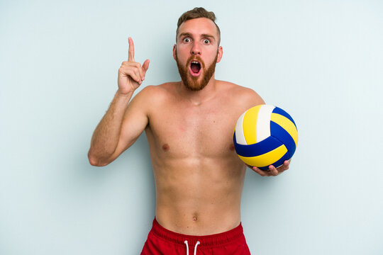 Young caucasian man playing volleyball isolated on blue background having an idea, inspiration concept.