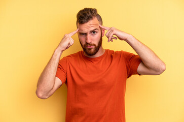 Fototapeta na wymiar Young caucasian man isolated on yellow background focused on a task, keeping forefingers pointing head.